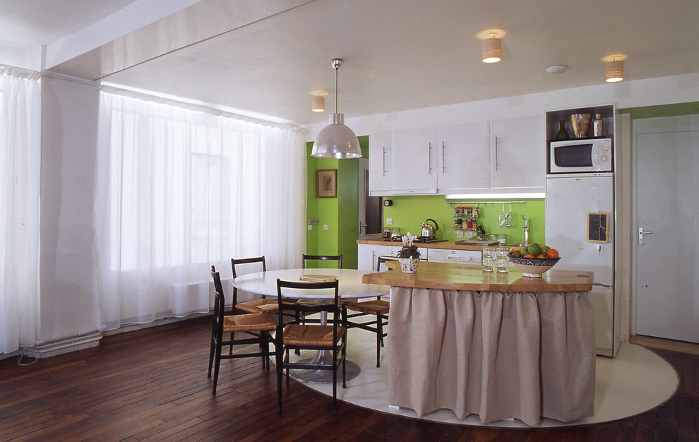 Idee per una cucina minimalista di medie dimensioni con lavello sottopiano, ante a filo, ante bianche, top in legno, paraspruzzi verde, paraspruzzi in legno, elettrodomestici bianchi e pavimento in cemento
