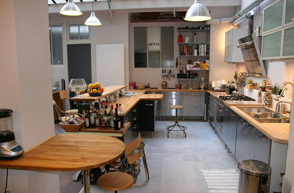 Foto di una cucina industriale di medie dimensioni con ante lisce, ante in acciaio inossidabile, top in legno, lavello a doppia vasca, pavimento con piastrelle in ceramica e penisola