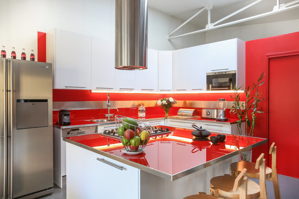 Idéer för ett stort modernt röd l-kök, med en undermonterad diskho, vita skåp, bänkskiva i glas, rött stänkskydd, rostfria vitvaror, betonggolv, en köksö, grått golv, släta luckor och glaspanel som stänkskydd