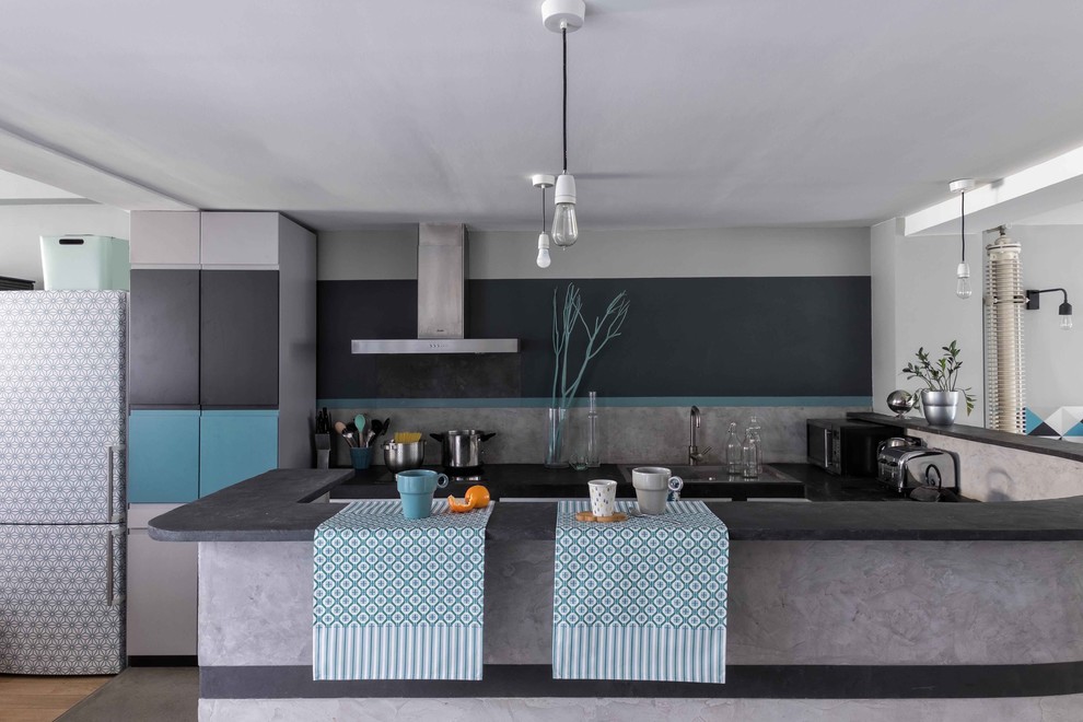 Foto de cocina industrial de tamaño medio con salpicadero verde, electrodomésticos de acero inoxidable, suelo de cemento y península