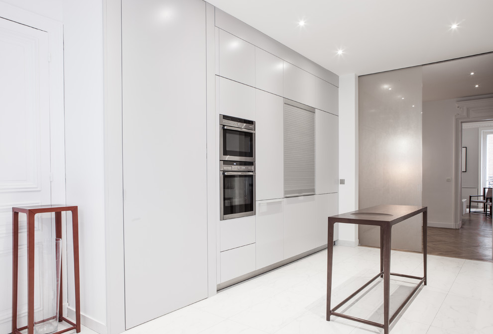 Inspiration pour une grande cuisine ouverte parallèle design avec des portes de placard blanches, une crédence blanche, un électroménager blanc et un sol blanc.