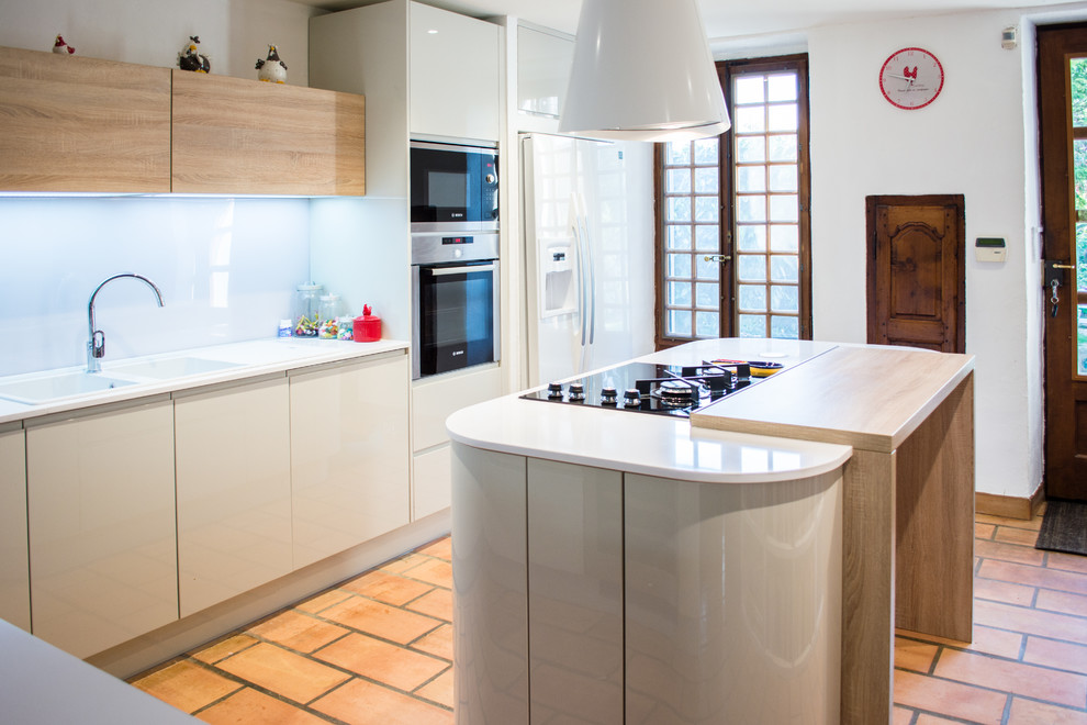 Design ideas for a large modern l-shaped open plan kitchen in Lyon with a double-bowl sink, beaded cabinets, beige cabinets, quartz worktops, white splashback, glass sheet splashback, stainless steel appliances, brick flooring, an island and red floors.