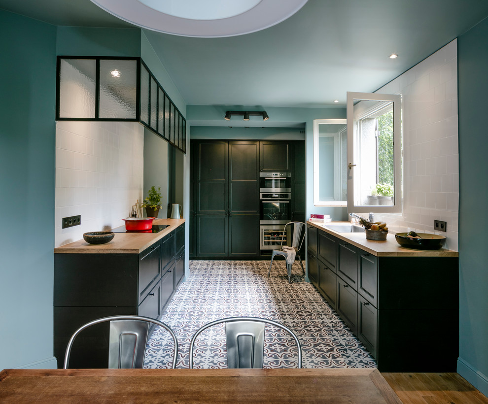 パリにある中くらいなトラディショナルスタイルのおしゃれなキッチン (アンダーカウンターシンク、緑のキャビネット、木材カウンター、白いキッチンパネル、セメントタイルのキッチンパネル、セラミックタイルの床、アイランドなし) の写真