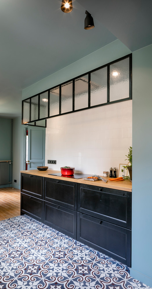 Photo of a medium sized contemporary galley kitchen in Paris with black cabinets, wood worktops, white splashback, matchstick tiled splashback, ceramic flooring and beige worktops.