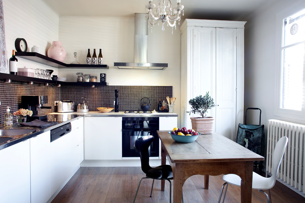 Свежая идея для дизайна: угловая кухня среднего размера в современном стиле с обеденным столом, белыми фасадами и черным фартуком без острова - отличное фото интерьера