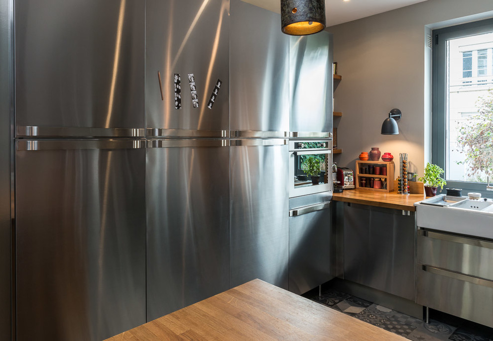 Imagen de cocina moderna de tamaño medio con fregadero integrado, puertas de armario en acero inoxidable, suelo de azulejos de cemento, península y suelo gris