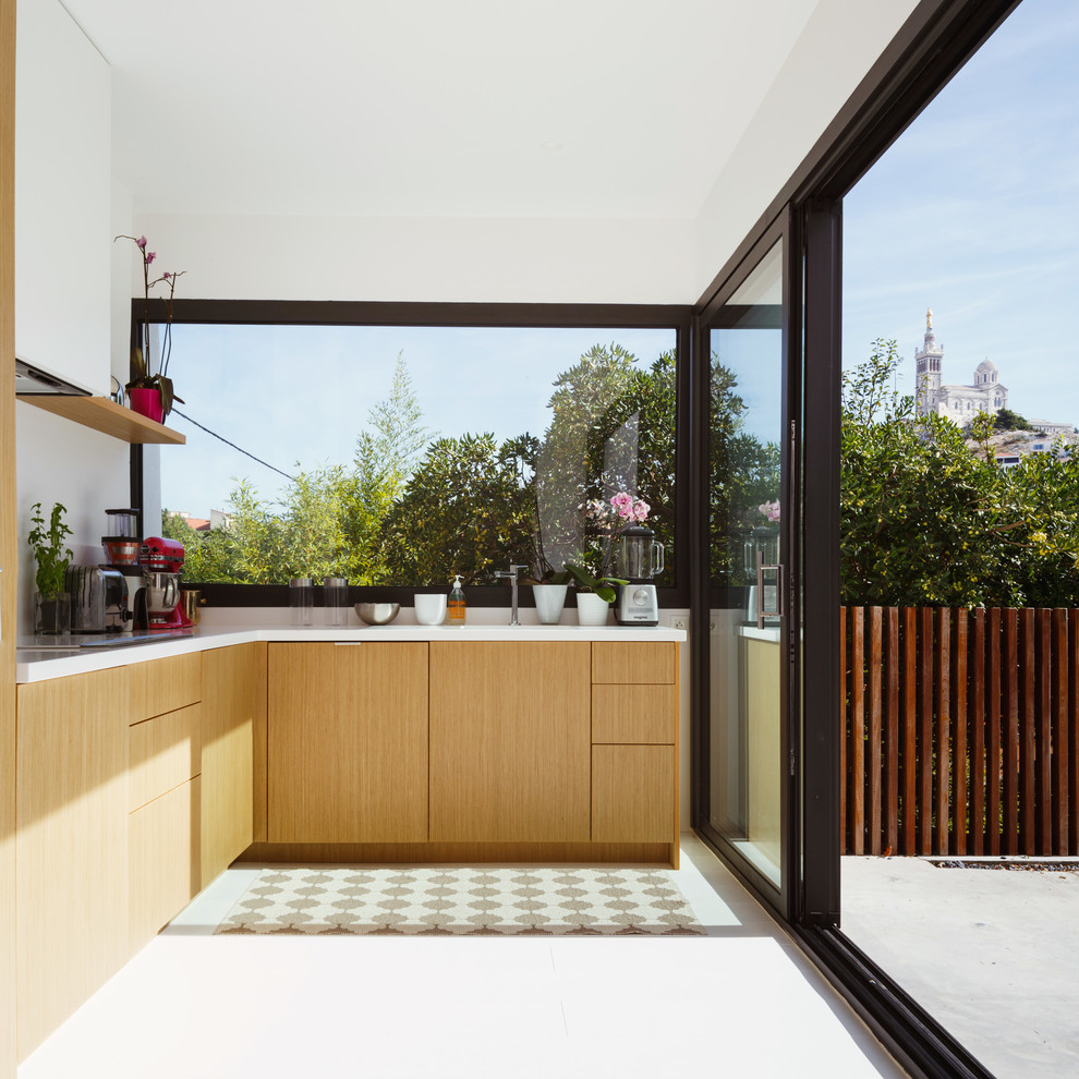 Cette photo montre une cuisine tendance en L et bois clair de taille moyenne et fermée avec un placard à porte plane et une crédence blanche.