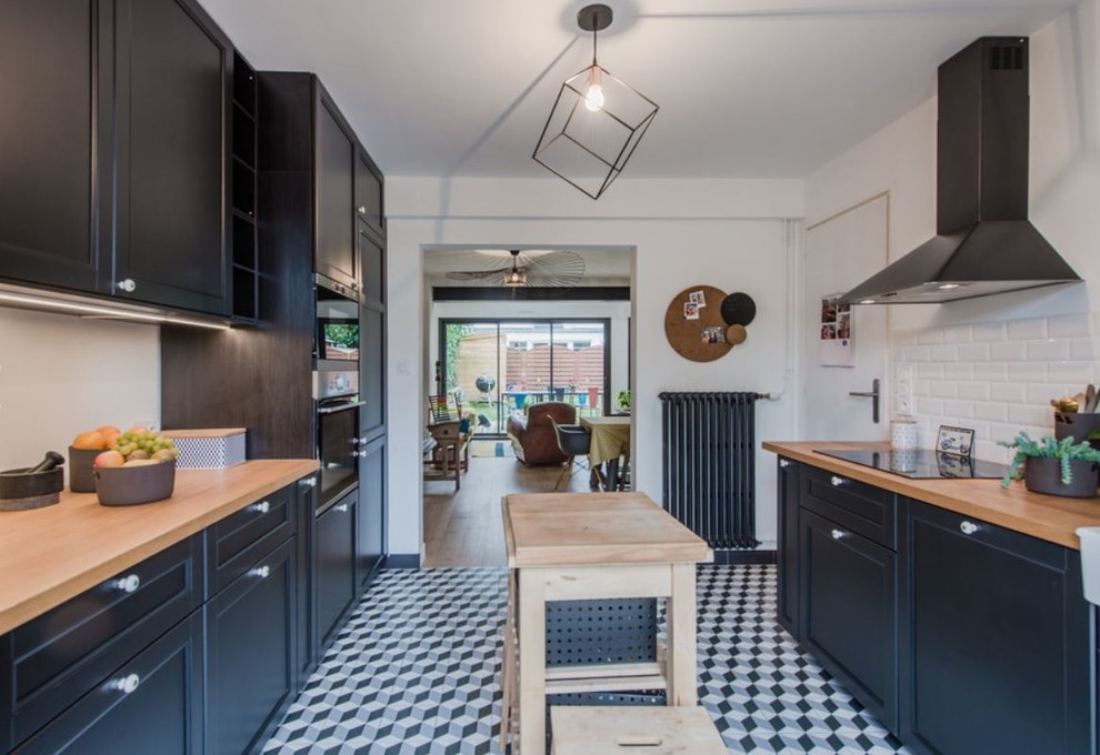 Foto di una cucina design di medie dimensioni con lavello stile country, ante nere, top in legno, paraspruzzi con piastrelle diamantate, elettrodomestici neri e pavimento in cementine