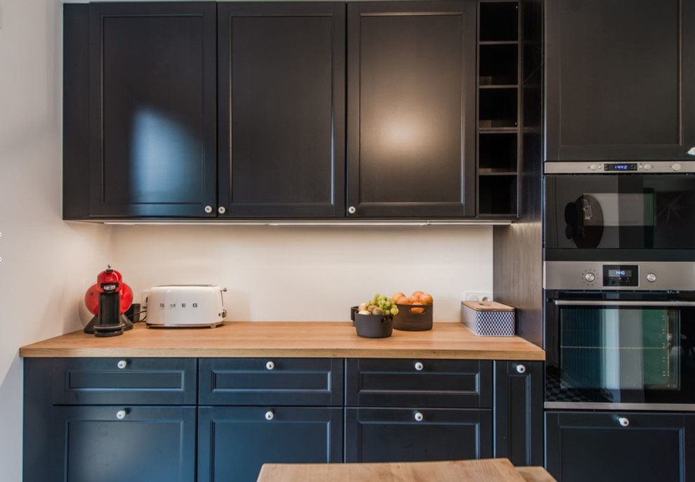 ナントにある高級な中くらいなエクレクティックスタイルのおしゃれなキッチン (エプロンフロントシンク、黒いキャビネット、木材カウンター、サブウェイタイルのキッチンパネル、黒い調理設備、セメントタイルの床) の写真