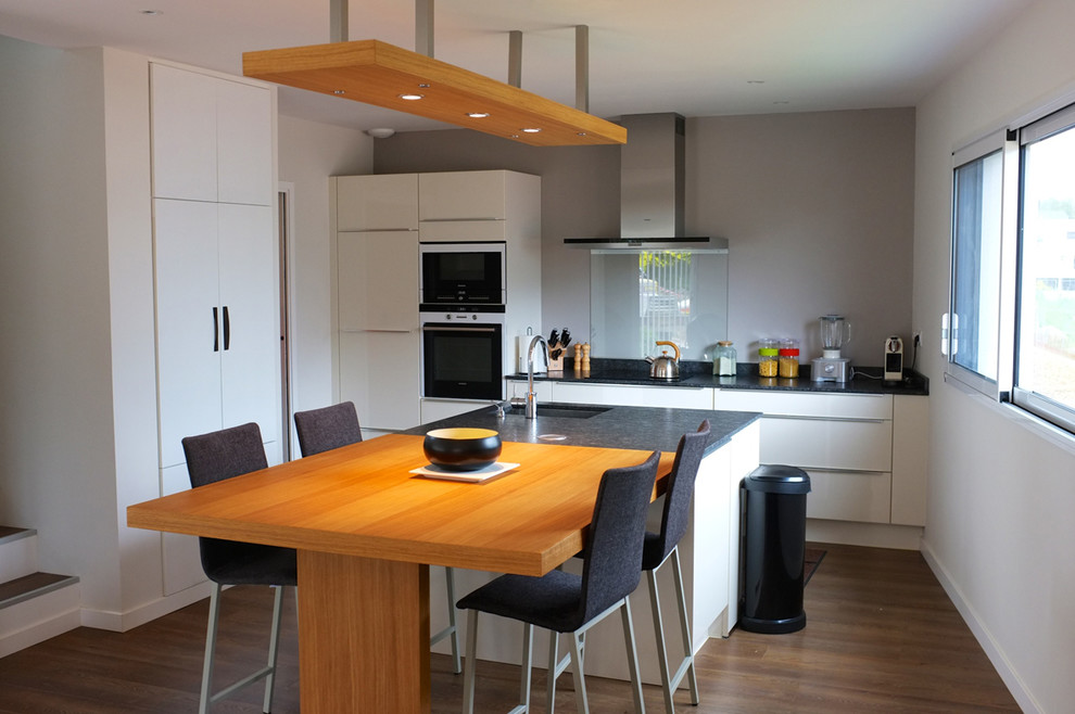 Источник вдохновения для домашнего уюта: большая параллельная кухня в современном стиле с обеденным столом, белыми фасадами и островом