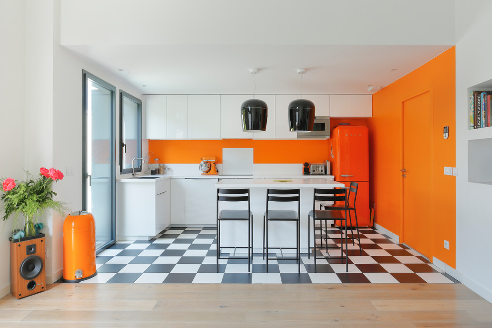 Trendy l-shaped multicolored floor kitchen photo in Paris with flat-panel cabinets, white cabinets, colored appliances, an island and white backsplash