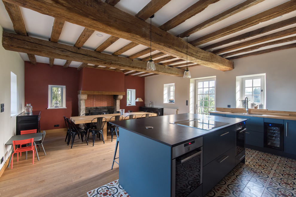 パリにある高級な広いカントリー風のおしゃれなキッチン (アンダーカウンターシンク、インセット扉のキャビネット、青いキャビネット、木材カウンター、茶色いキッチンパネル、木材のキッチンパネル、シルバーの調理設備、セラミックタイルの床、白い床) の写真
