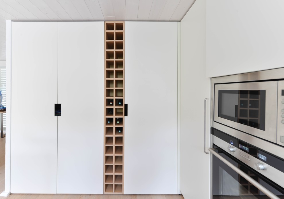 Esempio di una cucina contemporanea di medie dimensioni con ante bianche, elettrodomestici in acciaio inossidabile e parquet chiaro