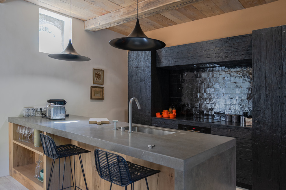 Bild på ett mellanstort lantligt grå grått kök, med en undermonterad diskho, bänkskiva i kalksten, svart stänkskydd, stänkskydd i terrakottakakel, integrerade vitvaror, kalkstensgolv, en köksö, grått golv, släta luckor och svarta skåp