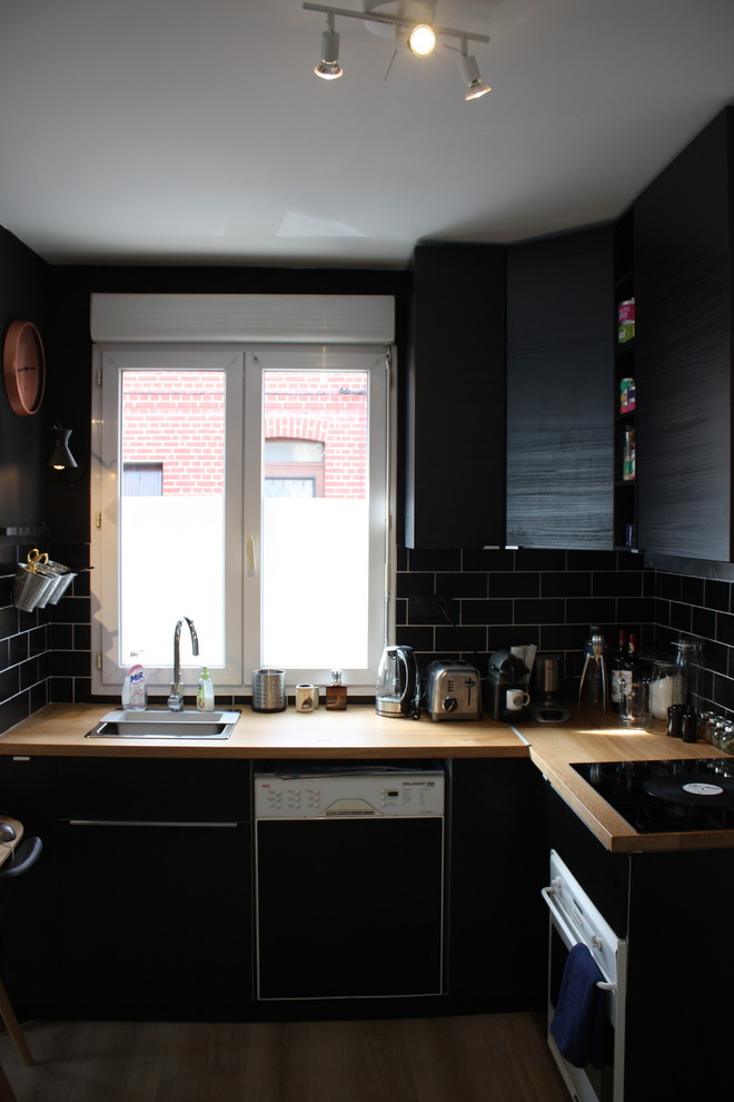 Inredning av ett minimalistiskt litet kök, med träbänkskiva, svart stänkskydd och laminatgolv