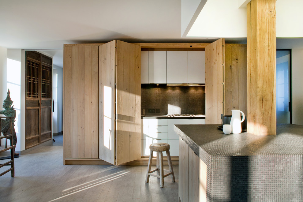 This is an example of a rustic single-wall open plan kitchen in Paris with flat-panel cabinets, brown splashback, mosaic tiled splashback, laminate floors, an island, brown floors, brown worktops and a drop ceiling.