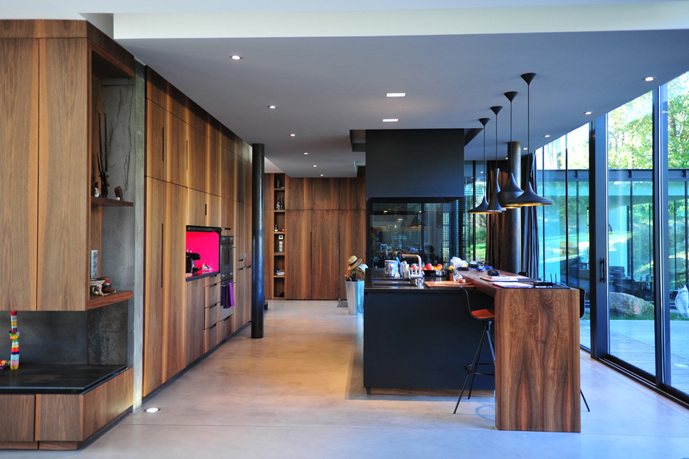 Idée de décoration pour une grande cuisine ouverte linéaire et bicolore design en bois foncé avec un plan de travail en bois, sol en béton ciré et îlot.