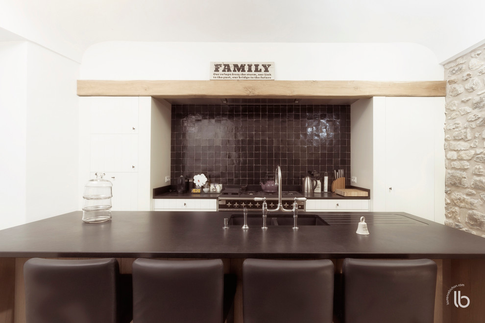 Foto de cocina comedor moderna de tamaño medio con fregadero de un seno, puertas de armario blancas, salpicadero marrón, salpicadero con mosaicos de azulejos, una isla y pared de piedra
