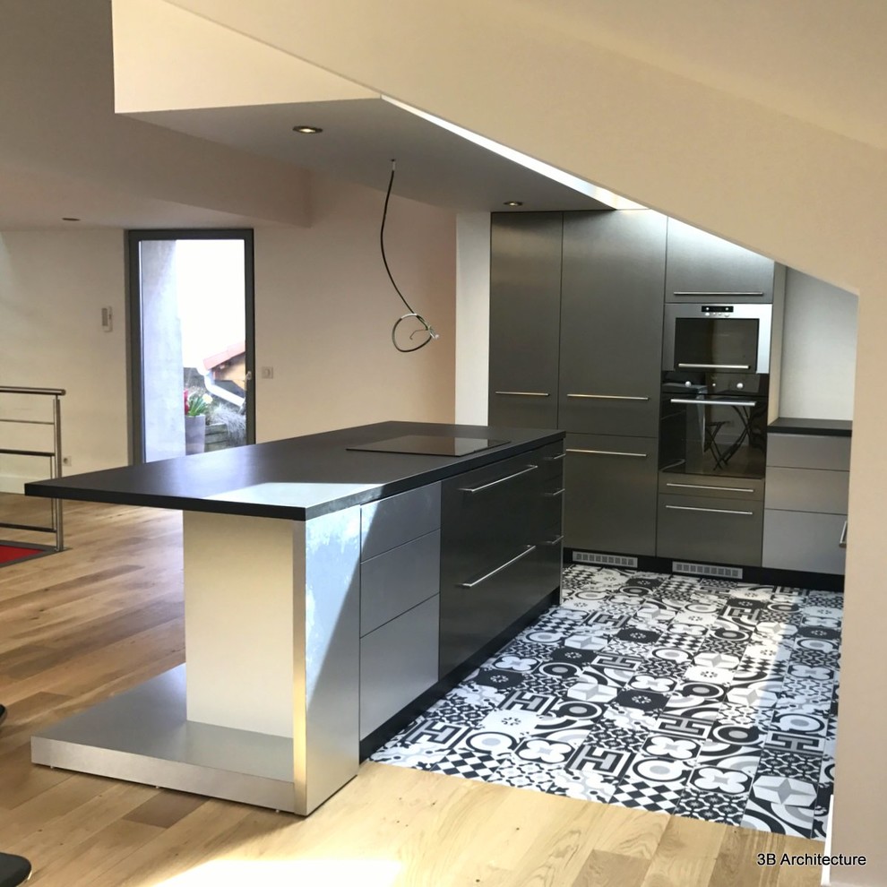 Inspiration for a medium sized contemporary kitchen in Nancy with a single-bowl sink, beaded cabinets, stainless steel cabinets, laminate countertops, stainless steel appliances, cement flooring and an island.