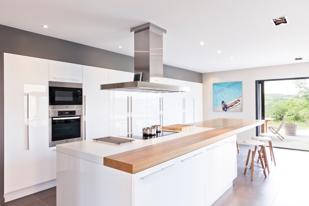 This is an example of a large contemporary single-wall kitchen/diner in Lyon with flat-panel cabinets, white cabinets and an island.