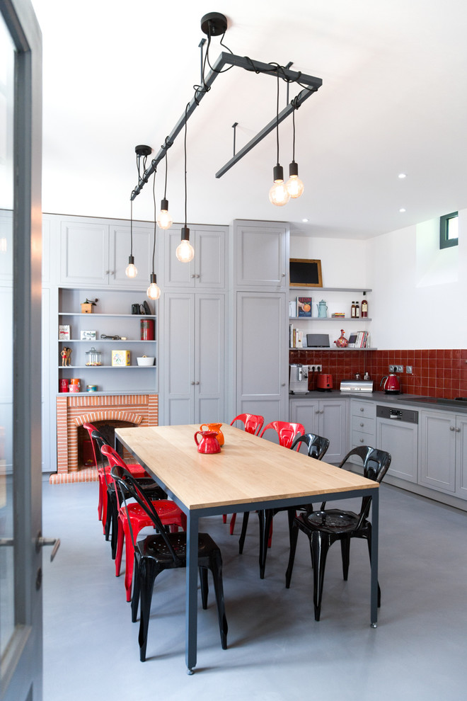 Idee per una cucina contemporanea con ante in stile shaker, ante grigie, paraspruzzi rosso, pavimento in cemento, nessuna isola e elettrodomestici colorati