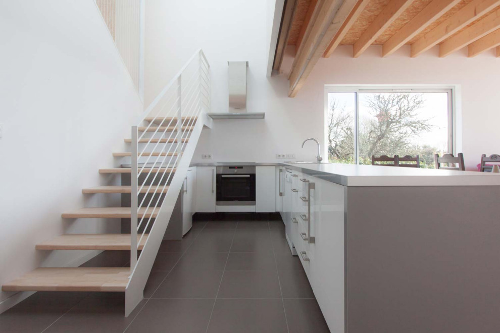 Foto på ett stort funkis grå linjärt kök med öppen planlösning, med en dubbel diskho, släta luckor, vita skåp, laminatbänkskiva, klinkergolv i keramik, en köksö och grått golv
