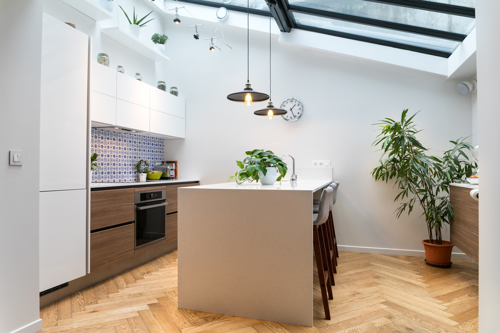 Immagine di una cucina design con ante lisce, ante bianche, paraspruzzi blu, pavimento in legno massello medio e pavimento marrone