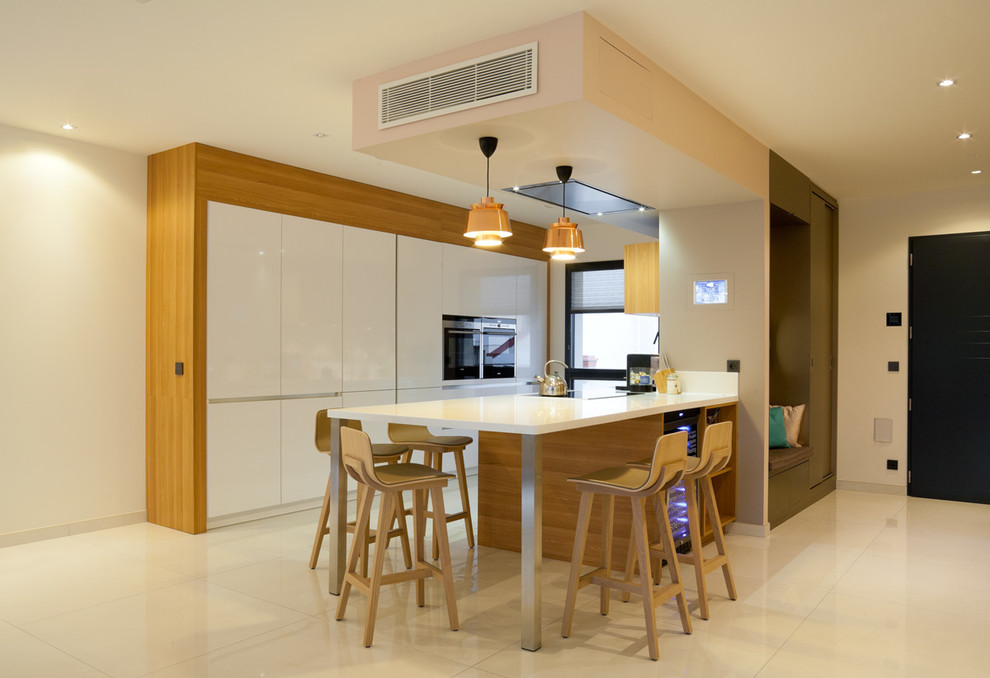 Пример оригинального дизайна: п-образная кухня-гостиная среднего размера в современном стиле с белыми фасадами, техникой из нержавеющей стали, полом из керамической плитки, полуостровом и барной стойкой