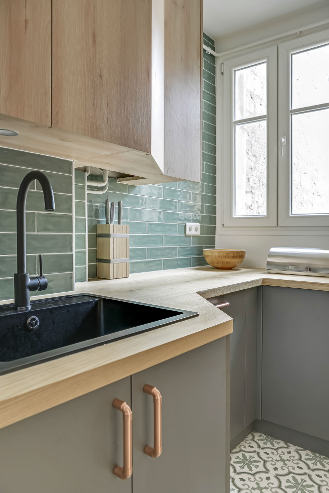 Urban single-wall cement tile floor and green floor enclosed kitchen photo in Paris with a single-bowl sink, beaded inset cabinets, light wood cabinets, wood countertops, green backsplash, subway tile backsplash, paneled appliances, no island and brown countertops