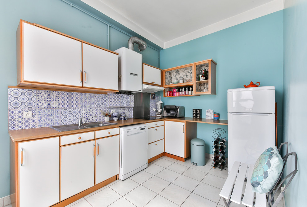 マルセイユにある低価格の中くらいなトラディショナルスタイルのおしゃれなキッチン (ドロップインシンク、フラットパネル扉のキャビネット、白いキャビネット、木材カウンター、白い調理設備、アイランドなし、青いキッチンパネル、セメントタイルのキッチンパネル) の写真