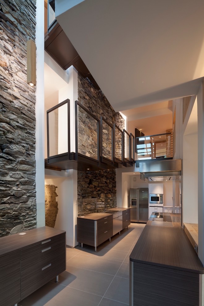 Foto de cocina lineal rústica de tamaño medio abierta con puertas de armario de madera en tonos medios, encimera de madera y pared de piedra