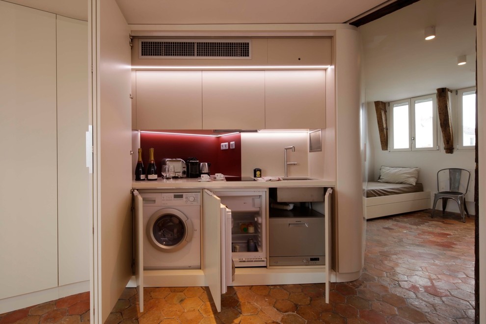 パリにある高級な小さなコンテンポラリースタイルのおしゃれなキッチン (アンダーカウンターシンク、フラットパネル扉のキャビネット、白いキャビネット、珪岩カウンター、赤いキッチンパネル、パネルと同色の調理設備) の写真