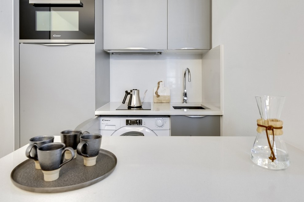 Idee per una piccola cucina minimalista con top in quarzite, lavello integrato, ante lisce, ante grigie, paraspruzzi bianco, elettrodomestici in acciaio inossidabile, pavimento in cementine, pavimento grigio e top bianco