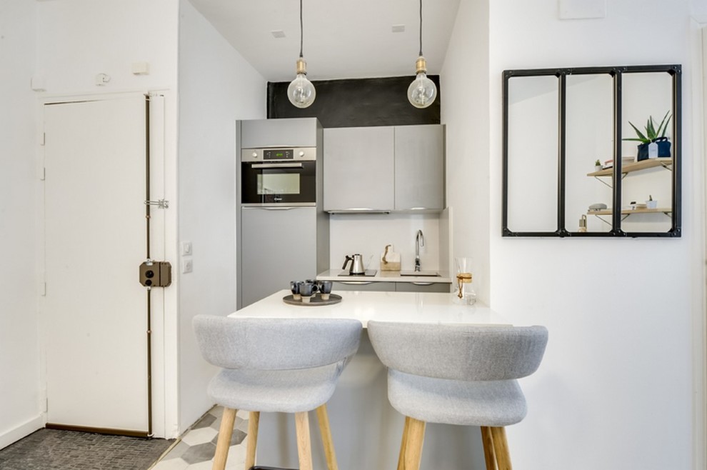 Immagine di una piccola cucina minimalista con top in quarzite, lavello integrato, ante lisce, ante grigie, paraspruzzi bianco, elettrodomestici in acciaio inossidabile, pavimento in cementine, pavimento grigio e top bianco