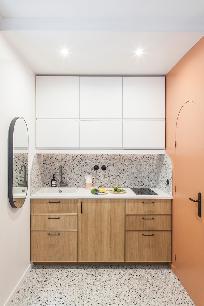 Photo of a small modern single-wall open plan kitchen in Paris with a single-bowl sink, beaded cabinets, light wood cabinets, laminate countertops, multi-coloured splashback, ceramic splashback, integrated appliances, terrazzo flooring, multi-coloured floors and white worktops.
