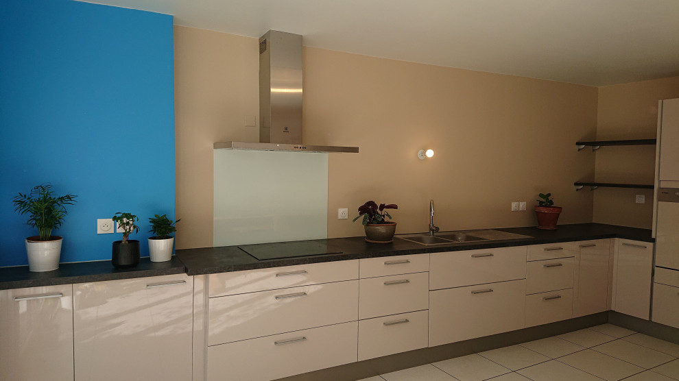 This is an example of a large modern l-shaped open plan kitchen in Other with a double-bowl sink, beaded cabinets, beige cabinets, granite worktops, beige splashback, glass sheet splashback, stainless steel appliances, porcelain flooring, beige floors and grey worktops.