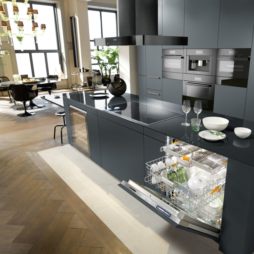 Imagen de cocina contemporánea grande abierta con una isla, puertas de armario negras, electrodomésticos negros y suelo de madera en tonos medios