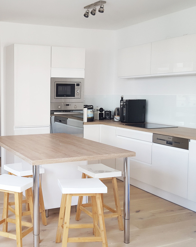 Esempio di una cucina scandinava di medie dimensioni con ante a filo, ante bianche, top in legno, paraspruzzi bianco, elettrodomestici in acciaio inossidabile, parquet chiaro e pavimento beige