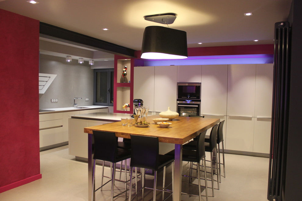 This is an example of a large contemporary open plan kitchen in Nancy with a single-bowl sink, white cabinets, quartz worktops, ceramic splashback, stainless steel appliances, ceramic flooring and an island.