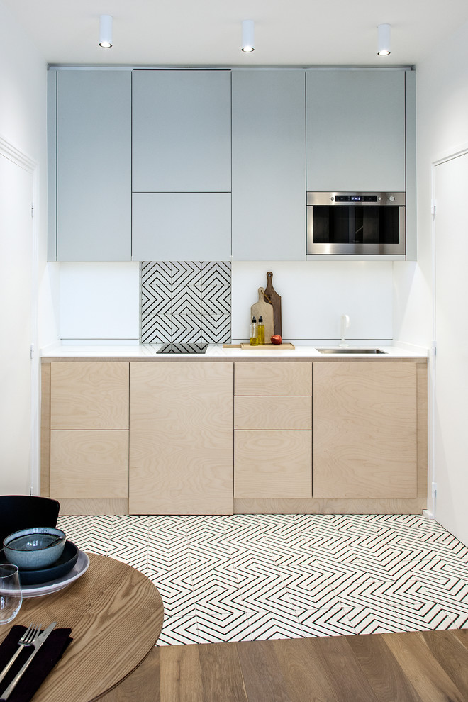 Idéer för ett mellanstort minimalistiskt vit linjärt kök med öppen planlösning, med en undermonterad diskho, skåp i ljust trä, vitt stänkskydd, luckor med profilerade fronter, bänkskiva i kvartsit, stänkskydd i keramik, integrerade vitvaror, cementgolv och flerfärgat golv
