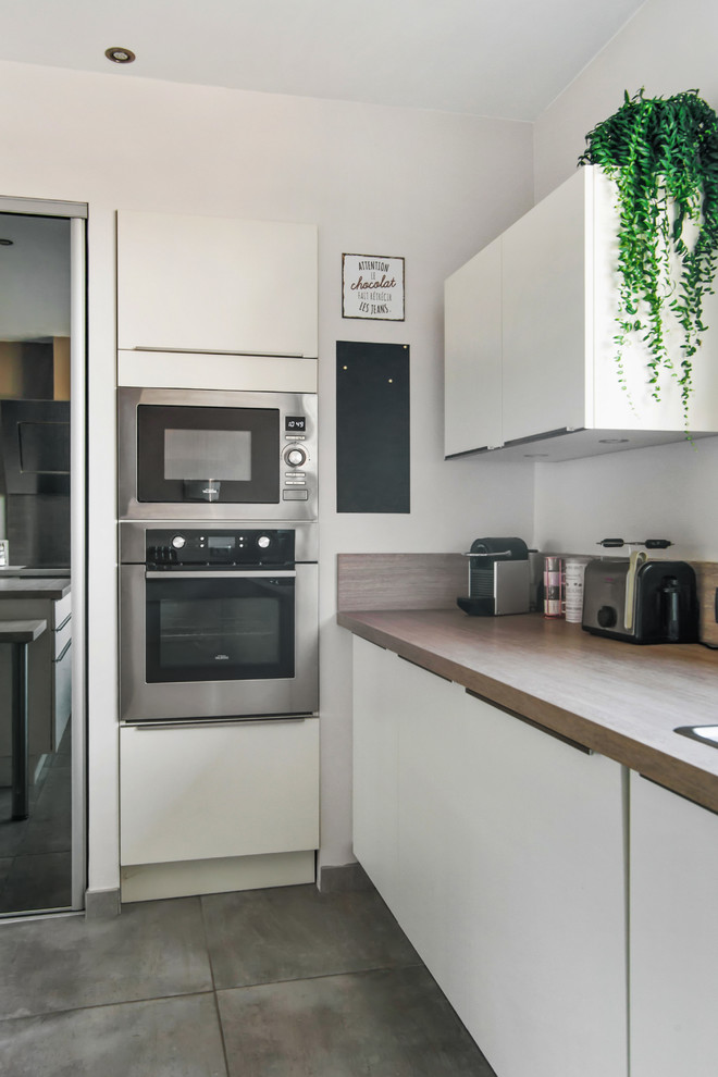 Foto på ett stort funkis grå kök, med släta luckor, vita skåp, laminatbänkskiva, integrerade vitvaror och en köksö