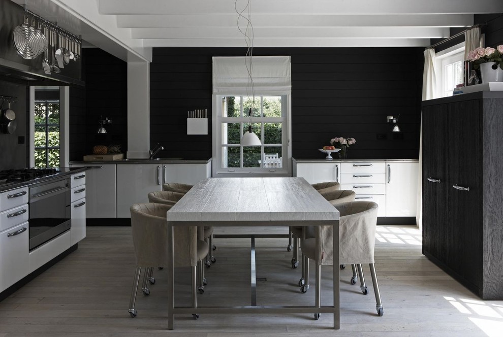 Источник вдохновения для домашнего уюта: большая угловая кухня в современном стиле с черным фартуком, обеденным столом и белыми фасадами без острова