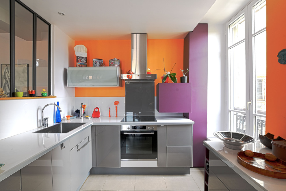На фото: п-образная кухня-гостиная среднего размера в современном стиле с фасадами с декоративным кантом, фиолетовыми фасадами, фартуком из стеклянной плитки, техникой под мебельный фасад и полуостровом с