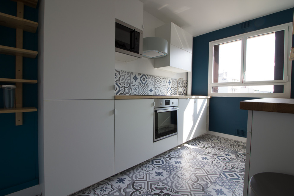 Idées déco pour une cuisine parallèle scandinave fermée et de taille moyenne avec des portes de placard blanches, un plan de travail en bois, une crédence en carreau de ciment, carreaux de ciment au sol et un sol bleu.
