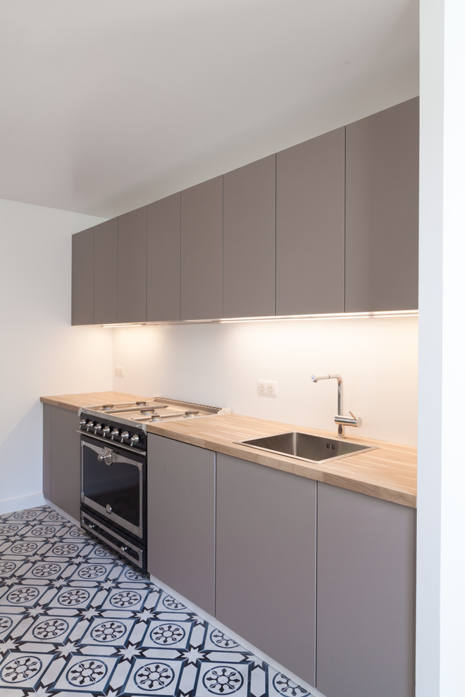 Foto på ett funkis kök, med en undermonterad diskho, luckor med profilerade fronter, grå skåp, träbänkskiva, vitt stänkskydd, integrerade vitvaror, mellanmörkt trägolv och en köksö