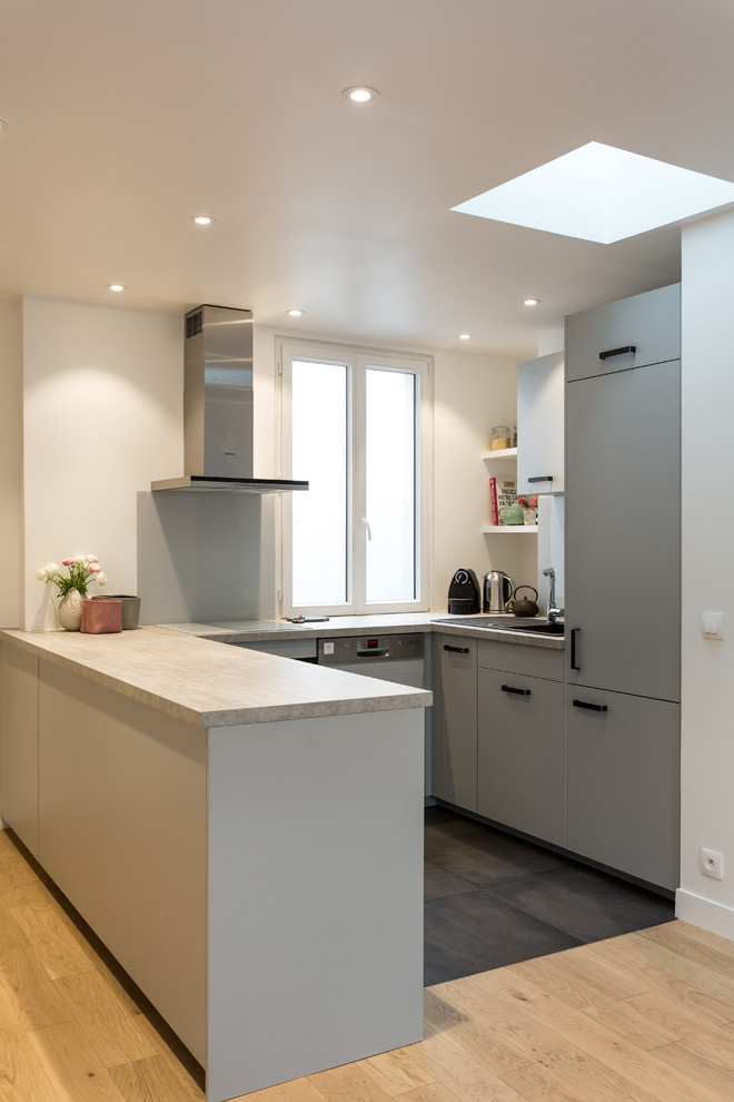 Design ideas for a medium sized eclectic u-shaped open plan kitchen in Paris with light hardwood flooring, no island, beige floors, a built-in sink, flat-panel cabinets, grey cabinets, laminate countertops, white splashback, glass sheet splashback, stainless steel appliances and grey worktops.