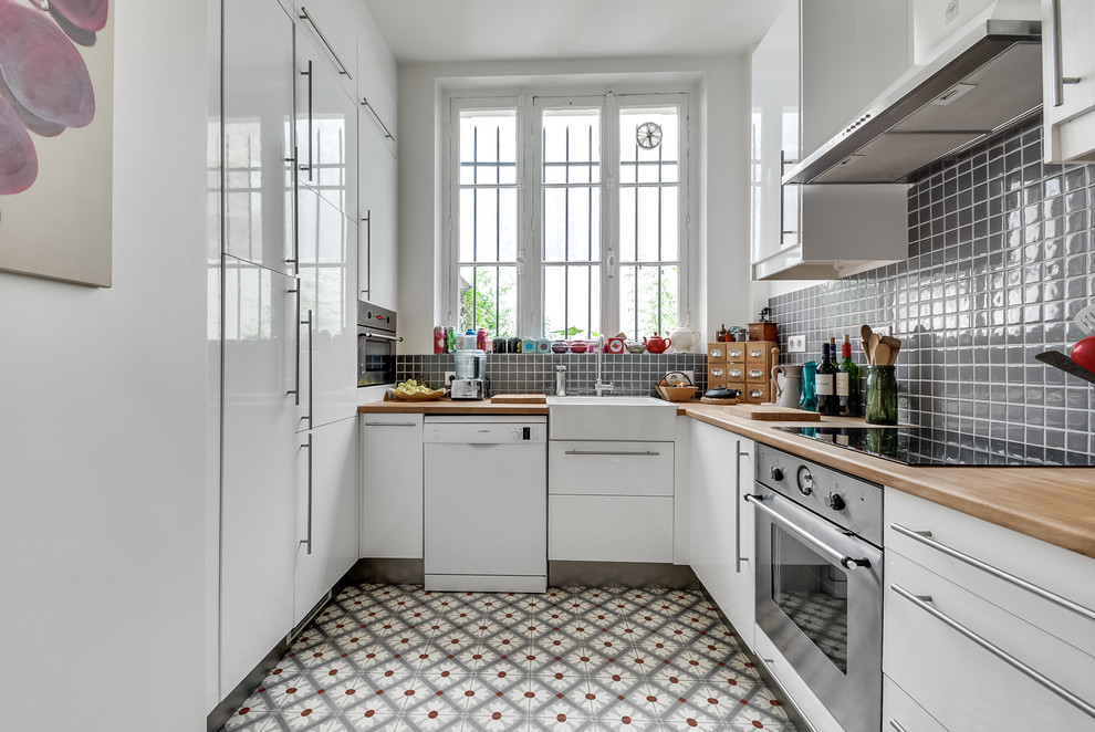 パリにあるお手頃価格の中くらいな北欧スタイルのおしゃれなキッチン (白いキャビネット、木材カウンター、グレーのキッチンパネル、シルバーの調理設備、アイランドなし、エプロンフロントシンク、インセット扉のキャビネット、モザイクタイルのキッチンパネル、セメントタイルの床) の写真