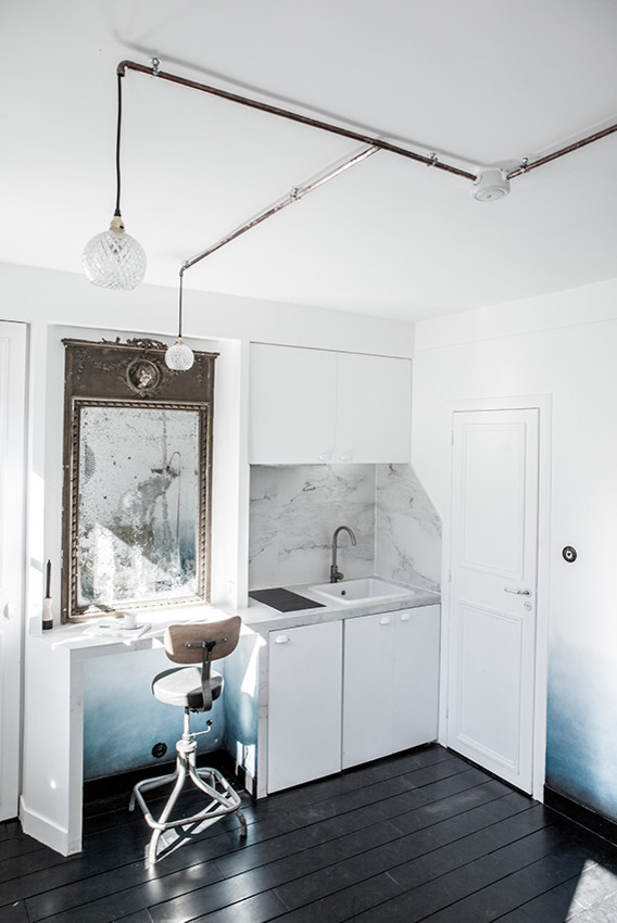 Cette image montre une petite cuisine ouverte linéaire nordique avec un évier posé, des portes de placard blanches, plan de travail en marbre, une crédence grise et parquet peint.