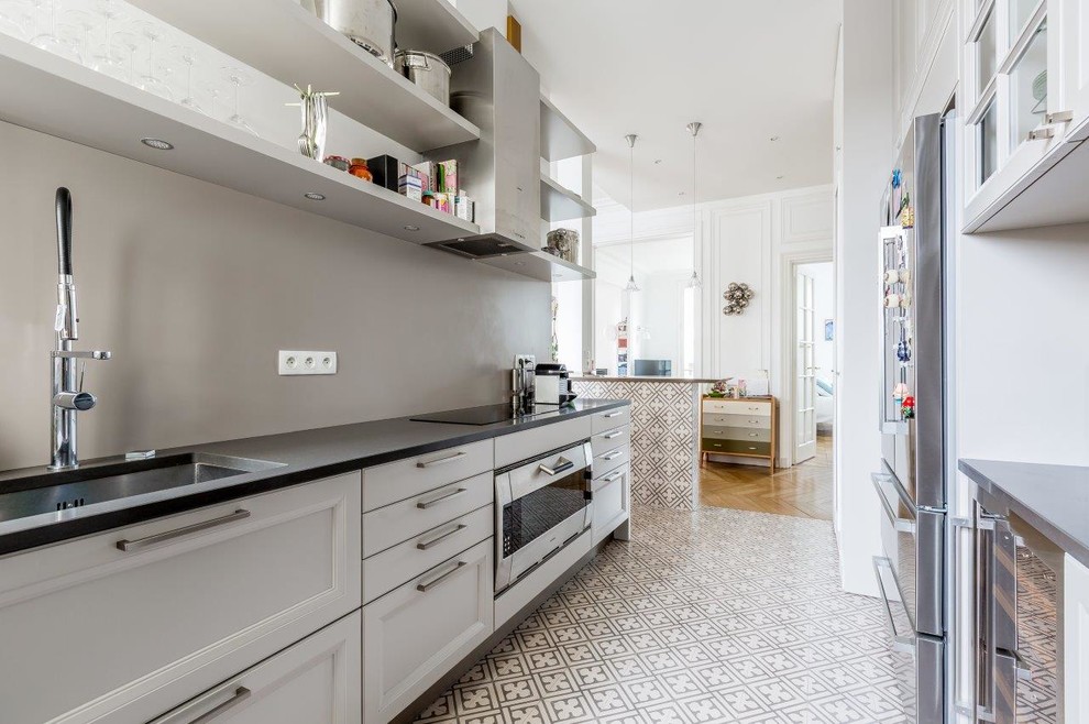 Geschlossene, Zweizeilige, Mittelgroße Moderne Küche in grau-weiß ohne Insel mit Unterbauwaschbecken, weißen Schränken, Küchenrückwand in Grau, Elektrogeräten mit Frontblende und Keramikboden in Paris