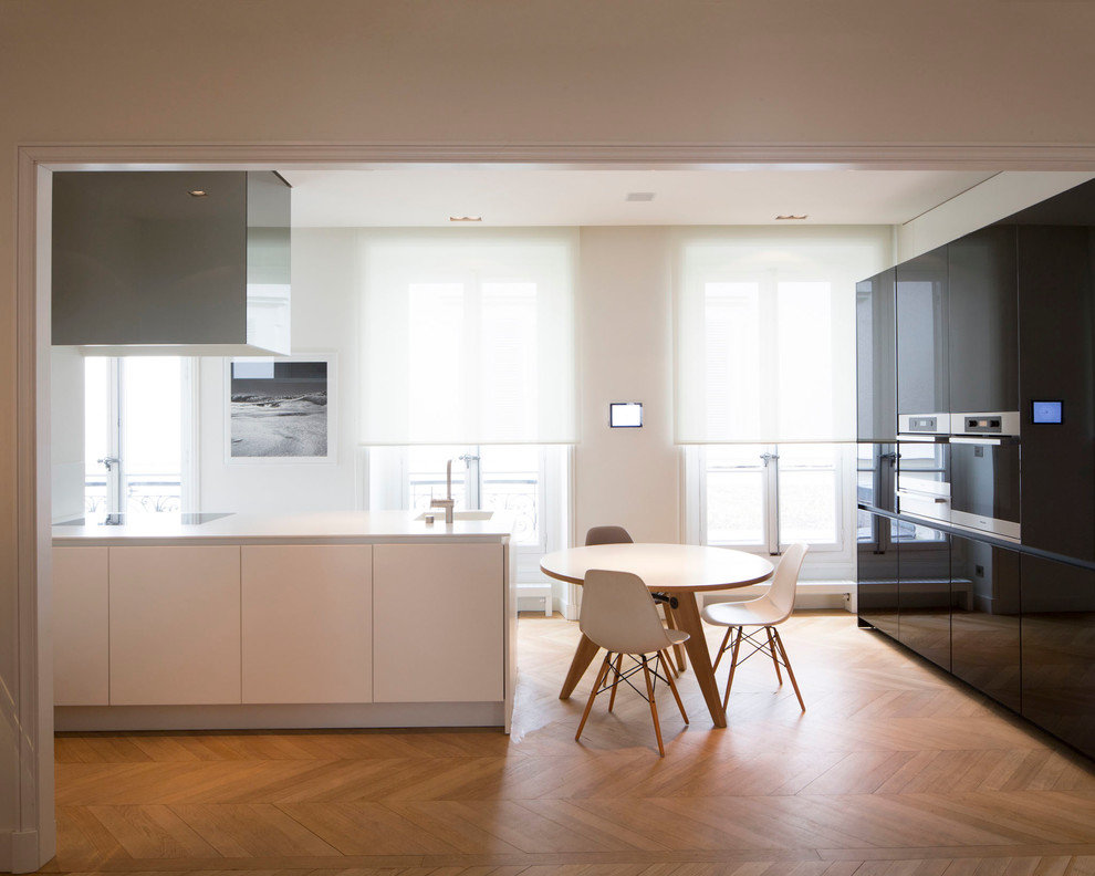 Große Moderne Wohnküche in L-Form mit schwarzen Schränken, braunem Holzboden und Halbinsel in Lyon